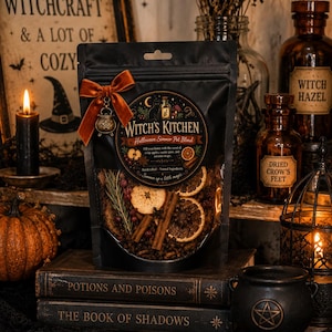 Pu&ograve; includere: Una busta nera richiudibile contenente un mix per pentola a cottura lenta di Halloween con fette di arancia essiccate, bastoncini di cannella ed erbe. L'etichetta riporta Witch's Kitchen Halloween Simmer Pot Blend. &Egrave; fissato un fiocco in velluto arancione bruciato con un ciondolo a forma di calderone in metallo.