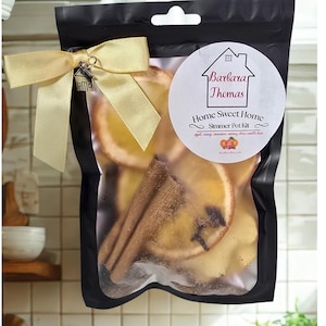 May include: A black bag containing a simmer pot kit, tied with a gold ribbon and a small house charm. The bag includes dried orange slices, cinnamon sticks, and a label that reads "Barbara Thomas Home Sweet Home Simmer Pot Kit."