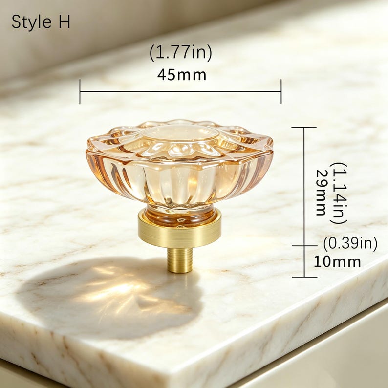 May include: Style H cabinet knob featuring a translucent amber-colored glass top with a scalloped edge and a brushed gold metal base. The knob measures 1.77 inches in diameter, 1.14 inches in height, and has a 0.39 inch threaded mounting post.