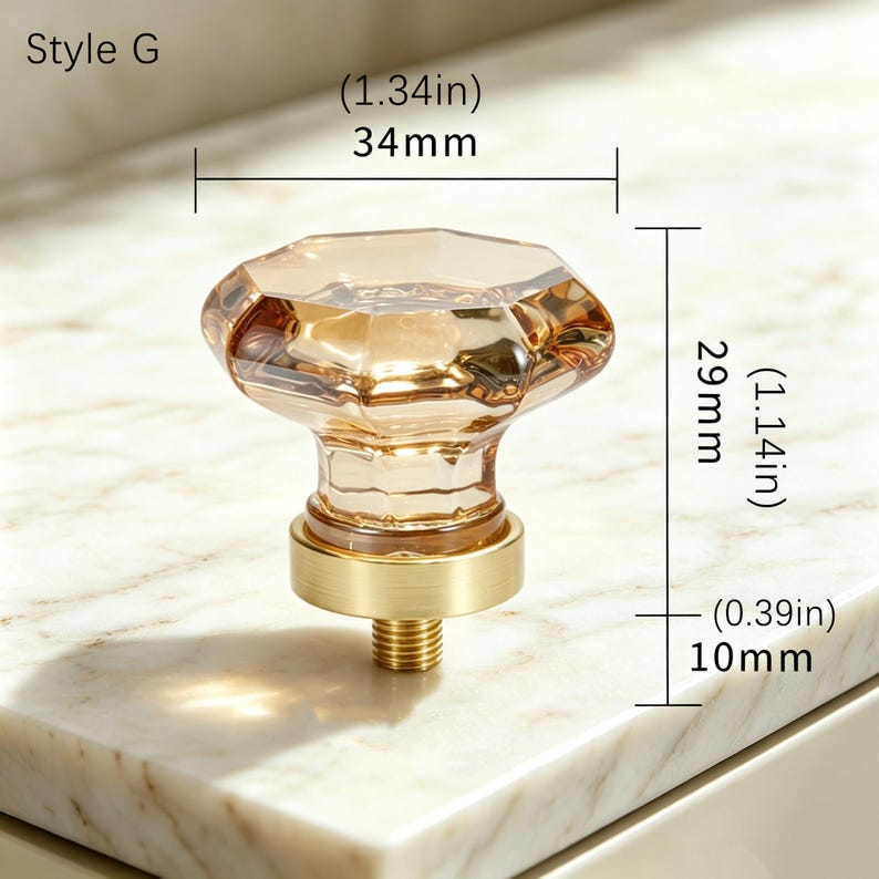 May include: Style G cabinet knob with a faceted, light amber-colored glass top and a brushed gold-tone metal base. The knob measures 1.34 inches wide, 1.14 inches high, and has a 0.39 inch threaded post for installation on furniture or cabinetry.