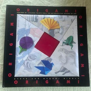 May include: A book titled "Origami" inspired by Japanese prints from the Metropolitan Museum of Art. The cover features a colorful origami design with a red square, a purple flower, a yellow fan, a blue bird, and a green frog.