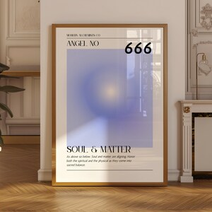May include: Framed art print in a gold-coloured frame. The artwork displays a gradient of blue and purple hues with a central yellow glow. Text includes "ANGEL NO 666" and "SOUL & MATTER". The print is displayed on a wooden floor.