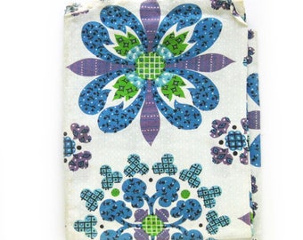 May include: A white fabric with a blue, green, and purple floral pattern. The fabric features a repeating design of stylized flowers with intricate details.