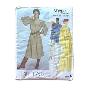 May include: Vogue Patterns American Designer sewing pattern envelope 2840 by Bill Blass. The front features illustrations of a high-neck dress with long billowy sleeves and a belted waist, shown in beige and yellow, plus a blue top with pants.