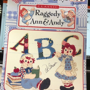 May include: Cross stitch pattern featuring Raggedy Ann and Andy, dressed in school clothes, with the letters A, B, and C. The pattern is titled "School Days" and is a classic Raggedy Ann and Andy design. The pattern is by Gloria and Pat and is dated September 1, 2001.