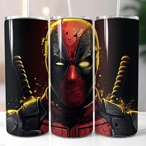 May include: A stainless steel tumbler with a black and red design featuring a close-up of Deadpool's face. The tumbler has a black lid and a straw.