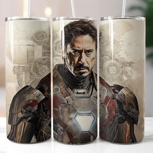 Puede incluir: Un vaso de acero inoxidable con un dise&ntilde;o que presenta a un superh&eacute;roe con un traje rojo y dorado. El fondo es una imagen descolorida de un dise&ntilde;o mec&aacute;nico.