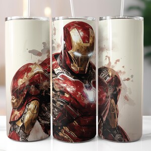 Peut inclure: Ensemble de trois gobelets en acier inoxydable avec une illustration de style aquarelle d'Iron Man. Le design pr&eacute;sente le personnage dans son armure rouge et or, avec des &eacute;claboussures de couleur sur un fond cr&egrave;me. Chaque gobelet a un couvercle blanc et une paille.