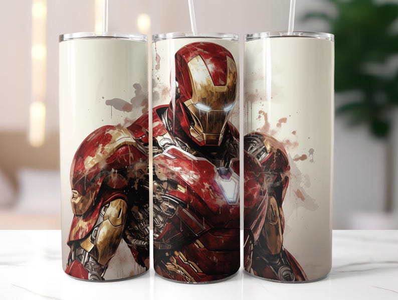 Peut inclure: Ensemble de trois gobelets en acier inoxydable avec une illustration de style aquarelle d'Iron Man. Le design pr&eacute;sente le personnage dans son armure rouge et or, avec des &eacute;claboussures de couleur sur un fond cr&egrave;me. Chaque gobelet a un couvercle blanc et une paille.
