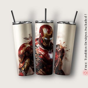 Peut inclure: Trois gobelets en acier inoxydable avec des motifs Iron Man. Les gobelets pr&eacute;sentent une illustration d'Iron Man rouge et or sur un fond cr&egrave;me. Chaque gobelet a une paille noire et un couvercle argent&eacute;. Le texte "8 FREE Tumbler Designs Included!" est visible.