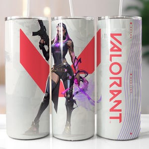 K&ouml;nnte beinhalten: Drei wei&szlig;e Edelstahlbecher mit Strohhalmen. Jeder Becher hat ein anderes Design. Einer hat eine rot-wei&szlig;e Grafik, ein anderer zeigt eine Figur mit einer Waffe und der dritte das Wort "VALORANT" in Rot.