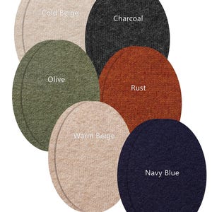 May include: Six oval-shaped felt coasters or mats arranged in a cluster. The colors are labeled as Cold Beige, Charcoal, Olive, Rust, Warm Beige, and Navy Blue. The text "More colors & sizes available" is printed at the bottom of the image.