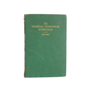May include: A vintage, green-covered book titled "The Tropical Subsistence Homestead" with gold lettering. The book's cover shows signs of wear, suggesting its age. The author's name, Gifford, is also printed on the cover.
