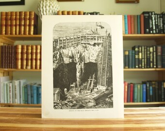 May include: A black and white illustration of a mine shaft entrance. The entrance is framed by wooden beams and a ladder leads down into the shaft. The text "Entrance of the Great Britain Coal Mine, 1878" is printed below the image.