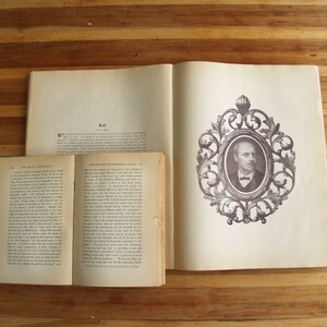 May include: Two open books with a brown wooden background. The book on the left has the title "The Holy Scripture" and the book on the right has the title "Revolution in the Nineteenth Century". The book on the right has a black and white portrait of a man in a decorative frame.