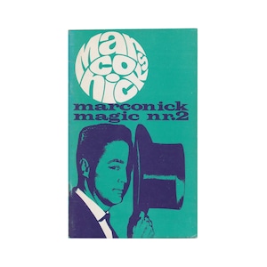 May include: A teal blue booklet with a purple circle containing the text "marconick" in white. The text "magic nr.2" is in purple below the circle. A man in a purple suit and a purple top hat is holding the hat in his right hand.