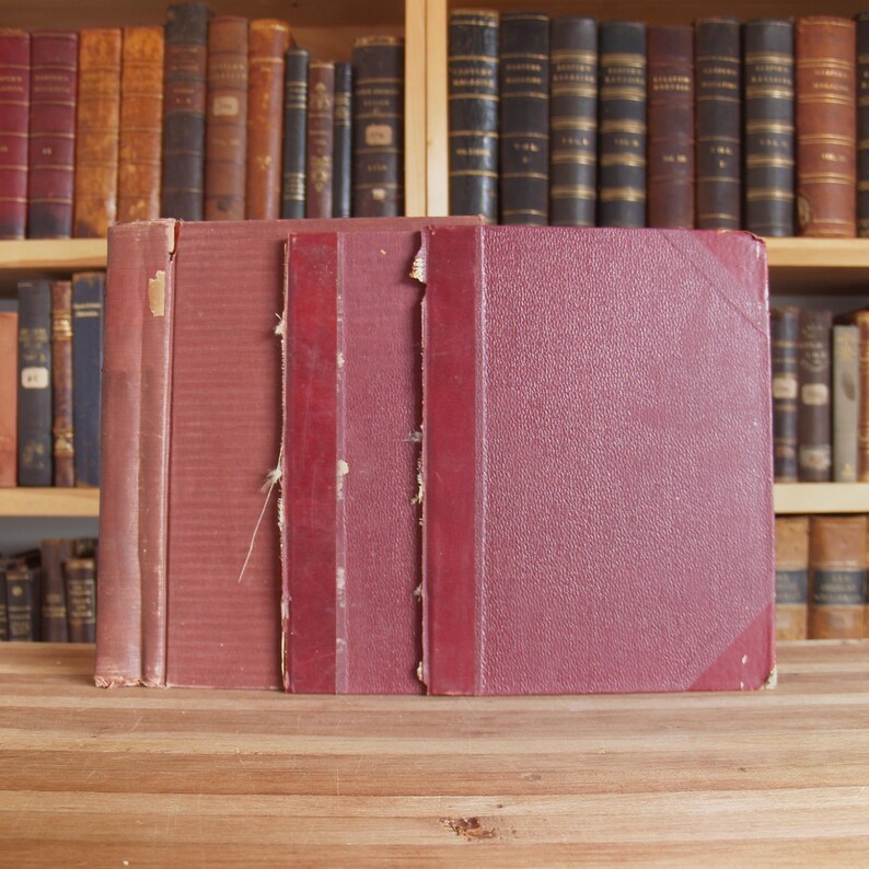 May include: Four burgundy-colored hardcover books with gold lettering on the spines. The books are stacked on a wooden surface.
