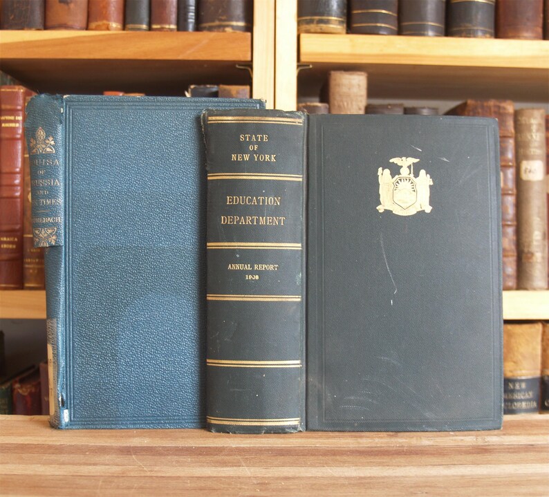 May include: Three vintage hardcover books with blue and black covers. The book on the left has the title "Russia of To-Day" and the book in the middle has the title "State of New York Education Department Annual Report 1908".