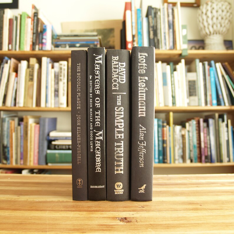 May include: Four black hardback books with white text on the spines. The titles are "The Simple Truth" by David Baldacci, "Masters of the Macabre" edited by Seon Manley and Coco Lewis, "The Bucolic Plague" by Josh Kilmer-Purcell, and "Lotte Lehmann" by Alan Jefferson.