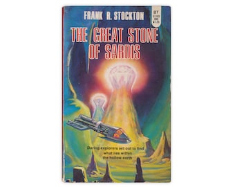 May include: A vintage paperback book cover with a colorful illustration of a spaceship flying towards a giant diamond in a cave. The title of the book is "The Great Stone of Sardis" by Frank R. Stockton.