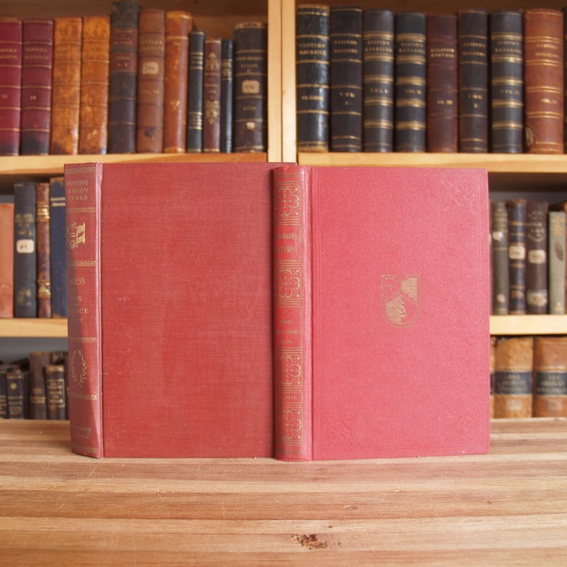 May include: A red hardcover book with gold lettering on the spine. The title is "The Works of Edgar Allan Poe" and the author is "Edited by Edmund Clarence Stedman and George Edward Woodberry".