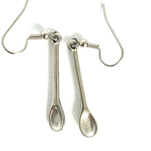 May include: A pair of silver spoon earrings with a simple design. The spoons are attached to silver hooks.