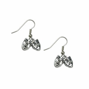 May include: A pair of silver dangle earrings featuring a pair of theater masks, one with a smiling face and the other with a frowning face.