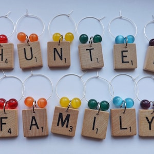 May include: Nine wine glass charms with colorful beads and wooden tiles spelling out "HUNTER FAMILY".