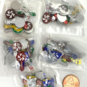 May include: A collection of small, colorful metal keys in various colors, including silver, red, green, and blue, are packaged in clear plastic bags. A penny is included for size reference.