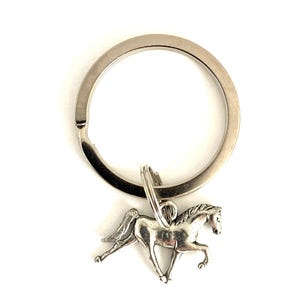 May include: Silver-toned horse keychain with a detailed running horse charm. The keychain has a large, circular ring for keys. The horse charm is a detailed miniature sculpture. The background is plain white.