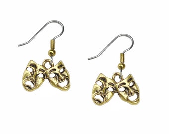 May include: A pair of gold-tone earrings featuring a pair of theater masks, one with a smiling face and the other with a frowning face.