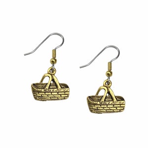 May include: A pair of gold-tone earrings featuring a small, detailed basket charm. The earrings have a simple hook closure.