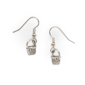 May include: A pair of silver earrings with a small basket charm hanging from each. The baskets are detailed with a woven pattern.