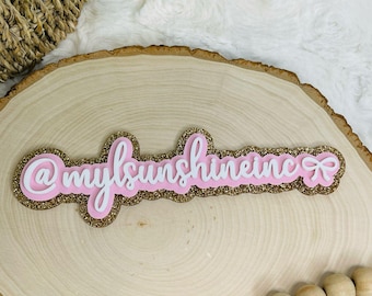 May include: Pink and gold glitter sign with the text "@mysunshineinc" and a pink bow.