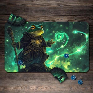 May include: A gaming mat featuring a green frog wizard with a staff, surrounded by swirling green energy and stars. Includes a deck of cards and blue dice. The artwork has a fantasy theme.
