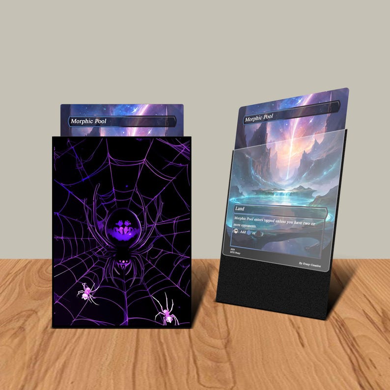 May include: A black card holder with a purple spider web design and the text "Morphic Pool". A card with a landscape scene is displayed in a black stand. The card holder and stand are on a wooden surface.