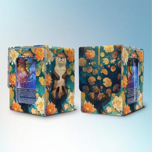 Puede incluir: Dos cajas de almacenamiento de cartas con un diseño floral turquesa y una ilustración de nutria. Las cajas están decoradas con flores naranjas y blancas. Las cajas están diseñadas para guardar cartas coleccionables.