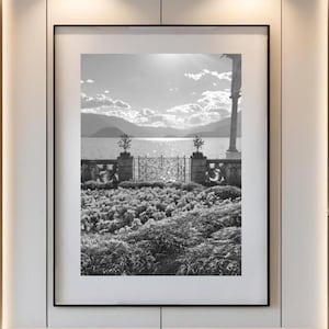 May include: A modern living room featuring a large black and white framed photograph of a landscape scene. The room includes a beige sofa, a round wooden coffee table, and a patterned rug. A beige armchair and a small side table are also present.