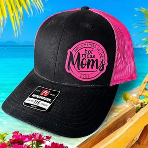 May include: Black and pink trucker hat with a pink circle logo that says "Proud Member of the Hot Mess Moms Club".