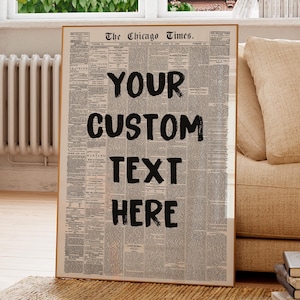 May include: A framed print featuring a vintage newspaper design with the headline "The Chicago Times." Bold black text reads "YOUR CUSTOM TEXT HERE." The print is displayed indoors, leaning against a wall near a window and a beige sofa.