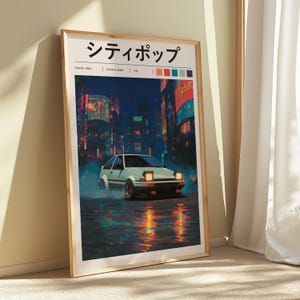 May include: Framed art print featuring a white sports car driving on a wet street at night. The artwork has a Japanese city theme with neon lights and the text "シティポップ". The print is in a wooden frame.