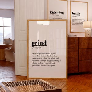 Puede incluir: Tres carteles motivacionales enmarcados con las palabras "execution", "hustle" y "grind" en texto negro sobre fondo blanco. El cartel "grind" incluye una definición. Los marcos son de color marrón claro y la habitación tiene pisos de madera.