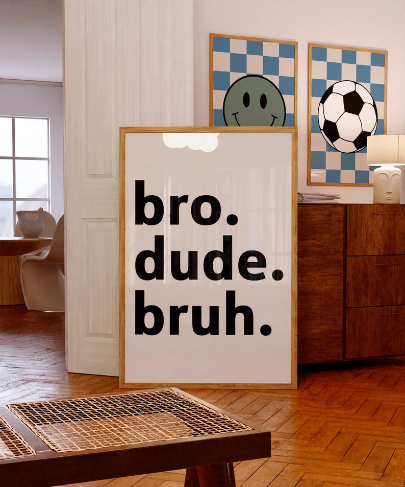 Puede incluir: Un cartel enmarcado con las palabras "bro. dude. bruh." en negrita negra. Se ven dos carteles enmarcados adicionales, uno con una carita sonriente y otro con un bal&oacute;n de f&uacute;tbol, ambos sobre un fondo a cuadros azul y blanco.