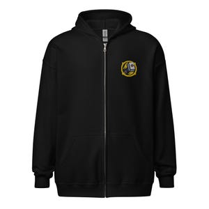 Può includere: Felpa con cappuccio nera con zip e un piccolo stemma ricamato sul petto sinistro. Lo stemma presenta un design giallo e nero con un elemento color argento. La felpa ha un cappuccio, una zip a tutta lunghezza e due tasche anteriori.