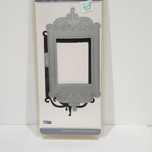 May include: A gray metal frame cookie cutter with an ornate design, packaged in clear plastic. The packaging includes the text "Cookie Cutter" and "Quickutz dies can both cut and emboss."