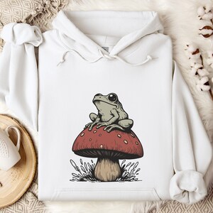 May include: White hoodie with a graphic of a green frog sitting on a red and white mushroom.