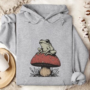 May include: A gray hoodie with a graphic of a green frog sitting on a red and white mushroom.