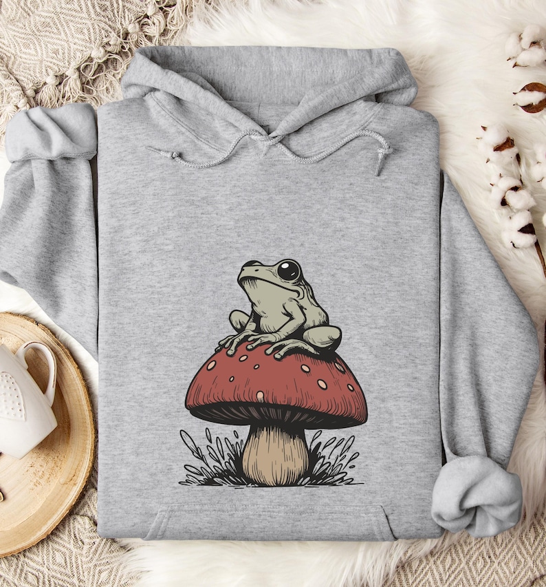 May include: A gray hoodie with a graphic of a green frog sitting on a red and white mushroom.