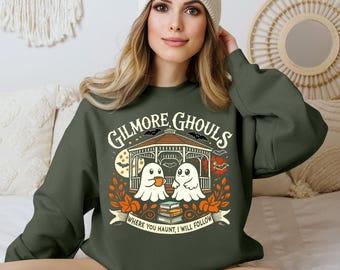 May include: Dark green sweatshirt with the text "Gilmore Ghouls" and a graphic of two cartoon ghosts in a gazebo. The design includes bats, books, and the phrase "Where you haunt, I will follow."