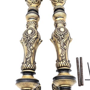 May include: Two ornate, antique-style door handles with a gold and black finish. The handles feature intricate floral and scrollwork designs, with a rounded base and top. Includes mounting hardware.